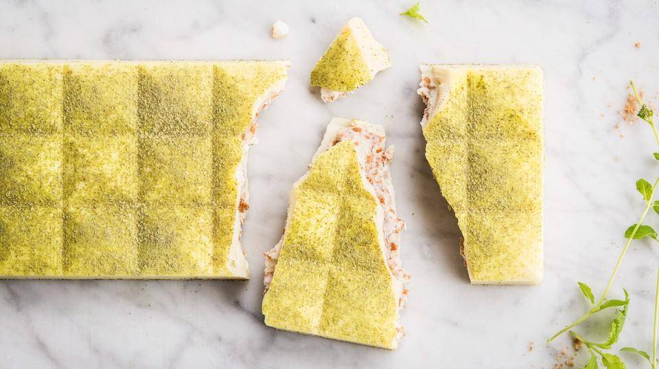 pieces of white chocolate tablet lightly dusted with green powder small mint leaves in lower right corner