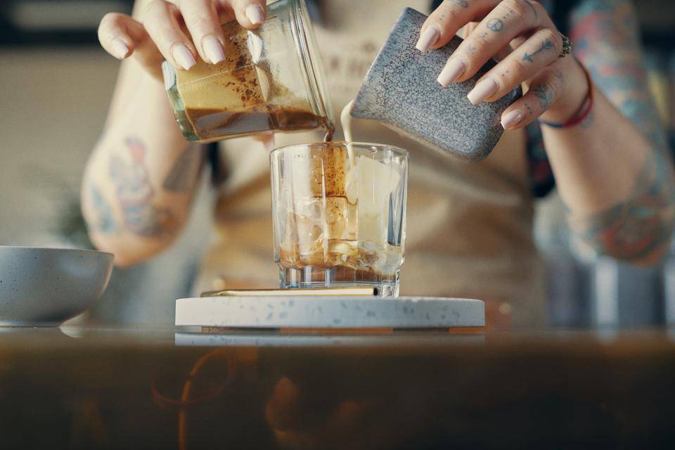 A servers hands seen mixing a creamy chocolate beverage