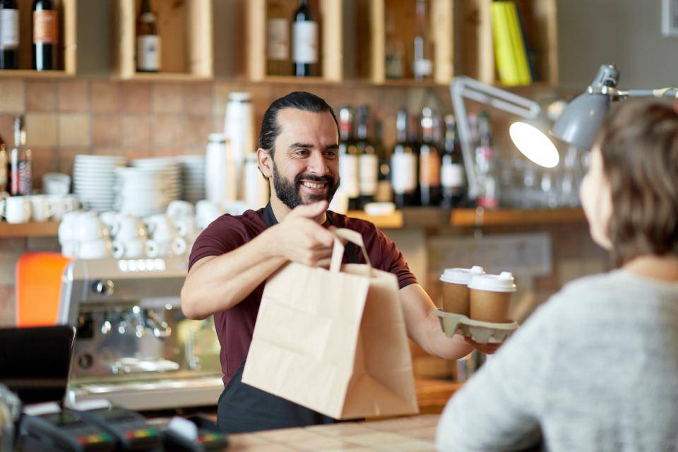 A shop owner hands a bag to a customer