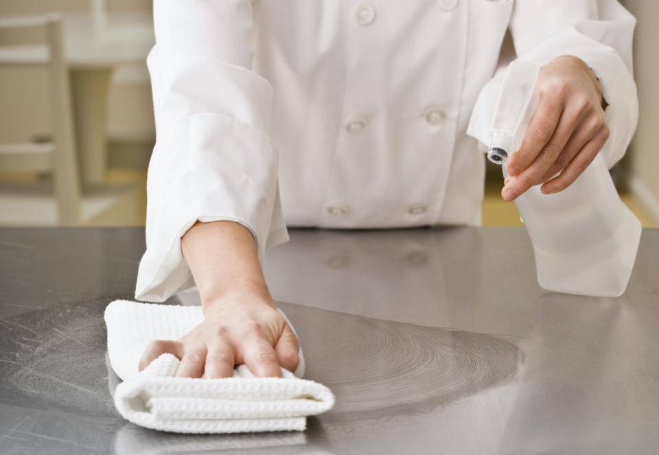 A chef sanitizes their workspace