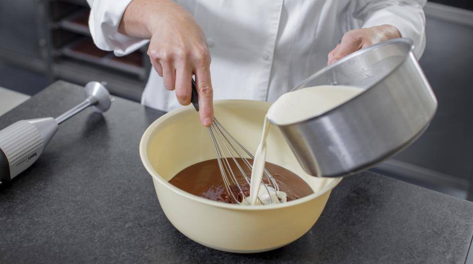 A chef adds cream to a ganache