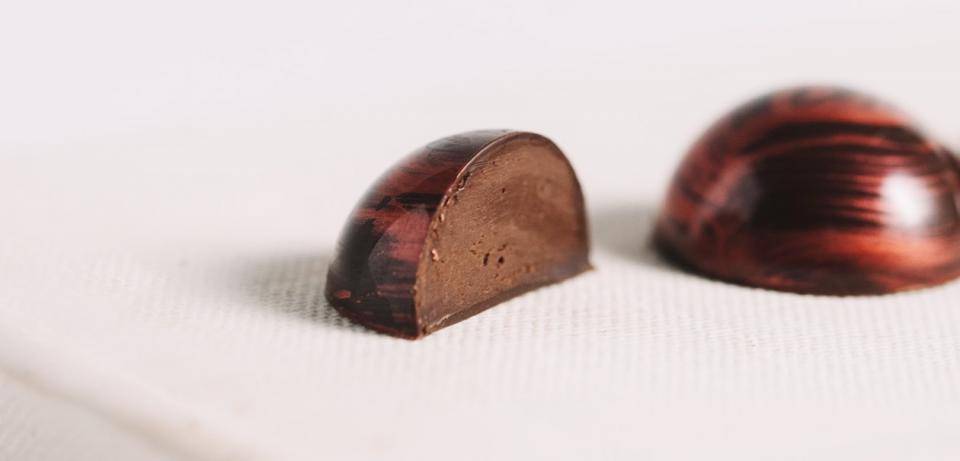 A molded bonbon cut in half to show ganache texture