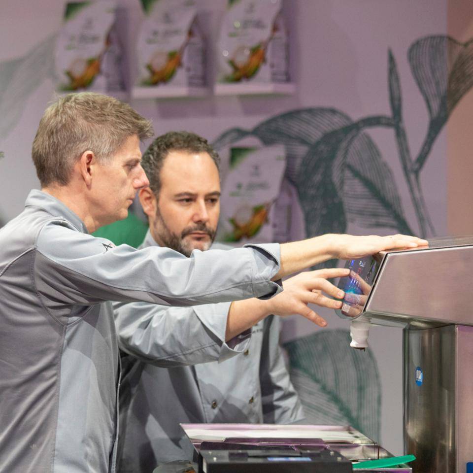 Two Chocolate Academy™ chefs adjust a Selmi tempering machine at the WCM finals