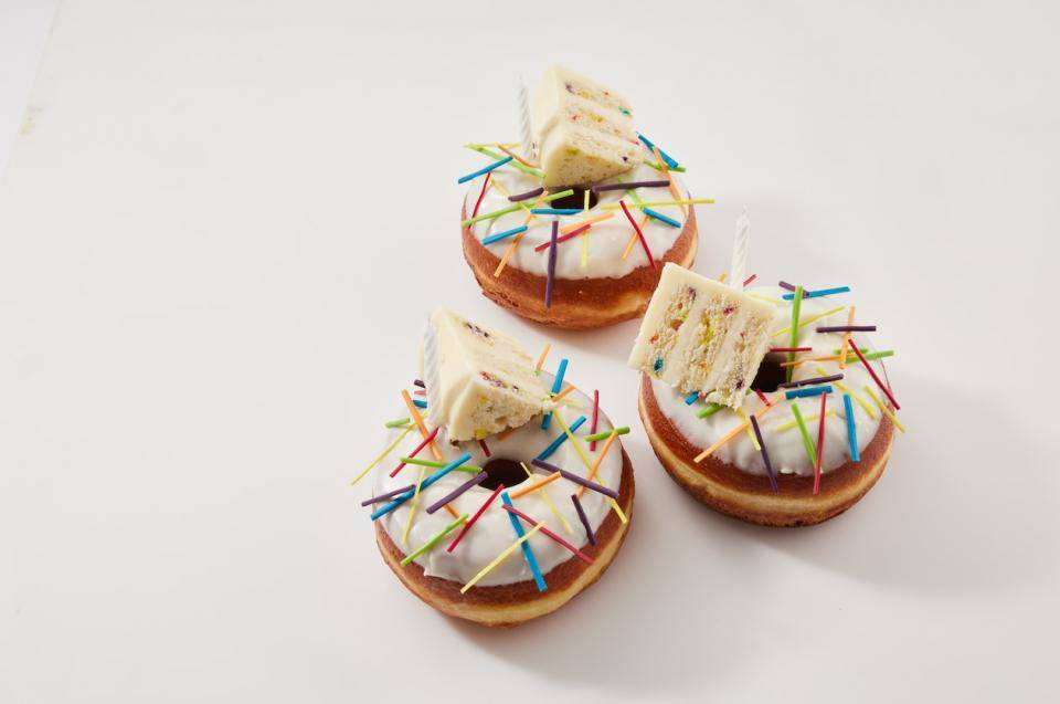 Doughnuts with multi-colored sprinkles and miniature wedges of birthday cake on top