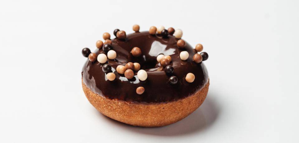 A plain cake doughnut, glazed with chocolate, and garnished with crunchy pearls