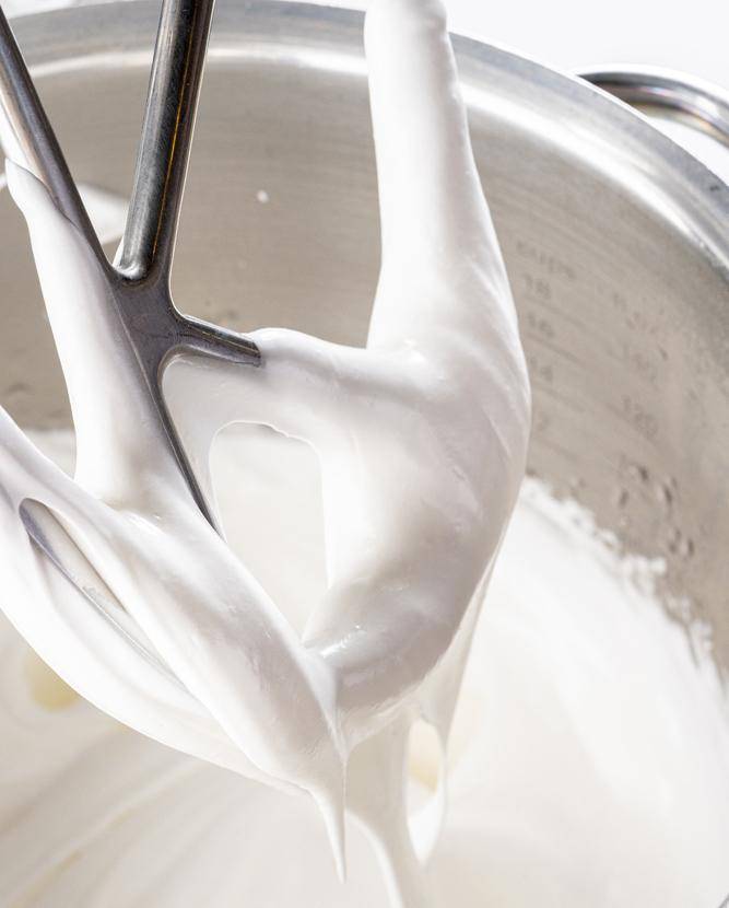 Royal icing being mixed in a stand mixer using the paddle attachement