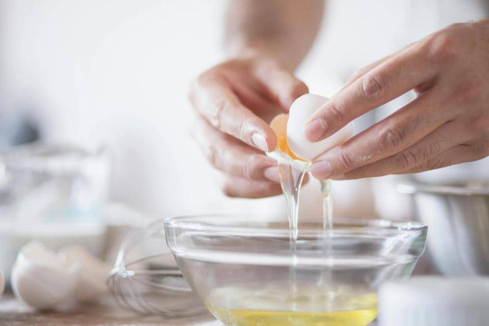 An egg being cracked over a bowl to collect just the white